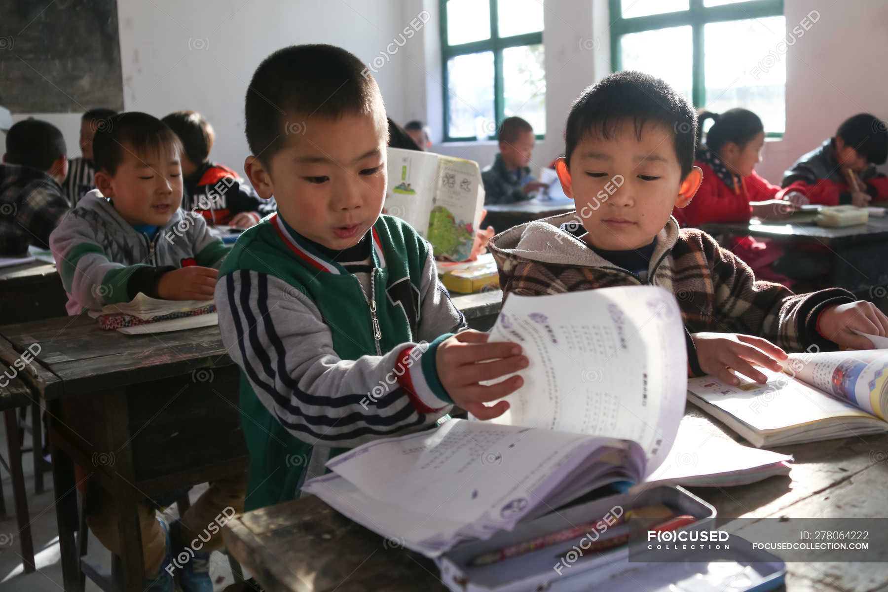 Chinese School Students Studying With Textbooks In Rural Primary School