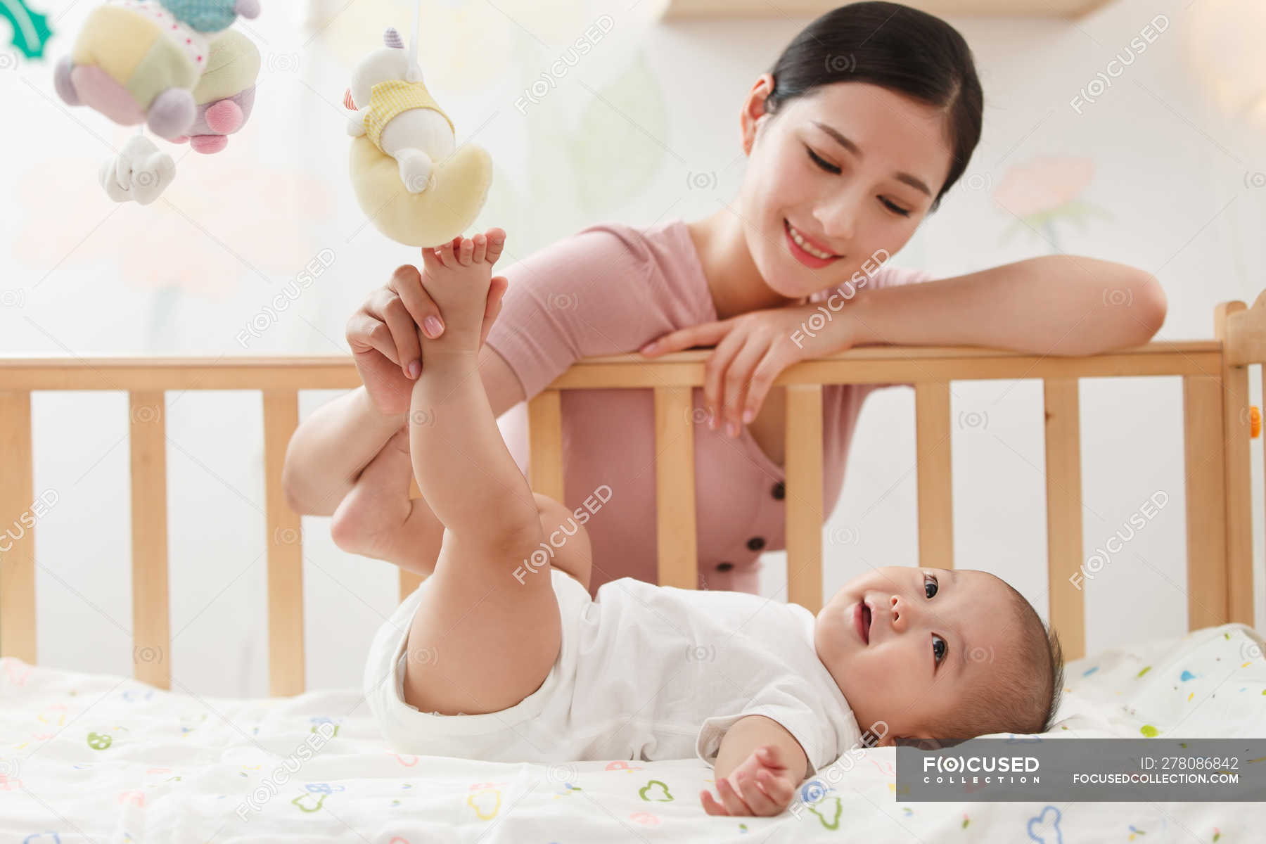 Smiling Young Mother Playing With Adorable Infant Baby Lying In