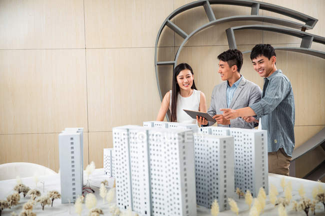 Smiling young architects using digital tablet and discussing project in office — Stock Photo