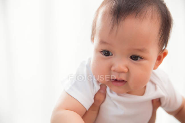 Cropped shot of parent carrying adorable asian baby at home — Stock Photo