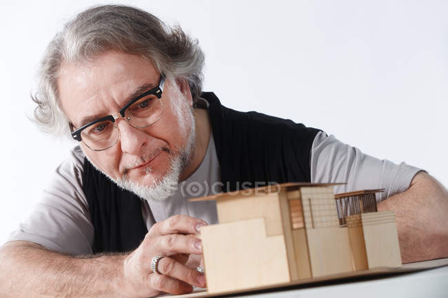 Serio concentrato professionale architetto maturo in occhiali da vista che lavorano con modello di costruzione sul posto di lavoro — Foto stock
