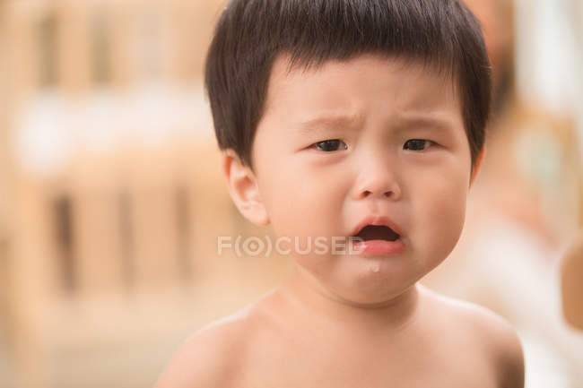 Portrait of upset asian baby with open mouth looking at camera — Stock Photo