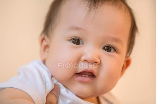 Vue rapprochée du parent portant bébé asiatique adorable regardant la caméra — Photo de stock