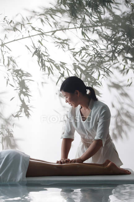 Обрезанный снимок массажистки, делающей массаж молодой женщине в спа — стоковое фото