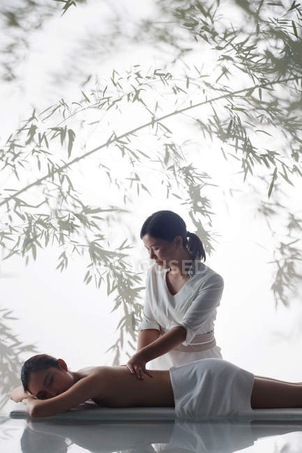 Вид збоку жінки масажистка робить масаж тіла молодої азіатки в спа-центрі — стокове фото