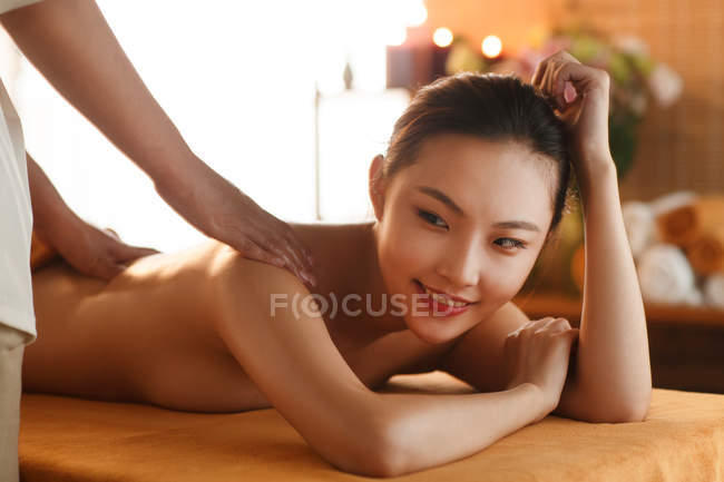 Vue rapprochée de belle jeune femme asiatique souriante recevant un massage au spa, plan recadré — Photo de stock
