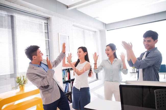 Щаслива молода азіатська бізнес команда святкує успіх і дарує один одному п'ять високих в сучасному офісі — стокове фото