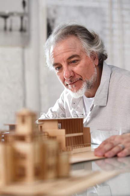 Профессиональный зрелый архитектор, работающий с моделью здания на рабочем месте — стоковое фото
