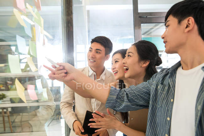 Молодые профессиональные азиатские предприниматели, работающие с липкими нотами в офисе — стоковое фото