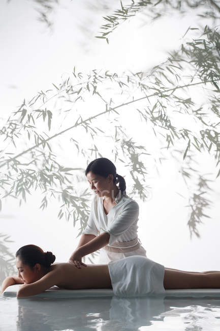 Vue latérale de la jeune femme asiatique recevant massage du corps au salon de spa — Photo de stock