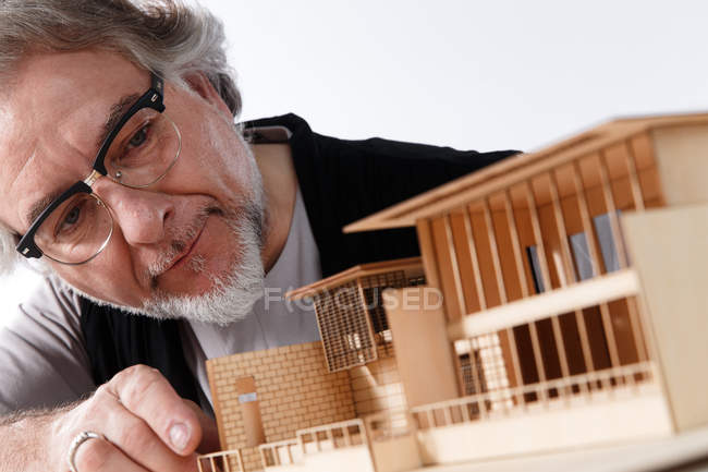 Професійний зрілий архітектор в окулярах, що працює з проектом будівельної моделі на робочому місці — стокове фото