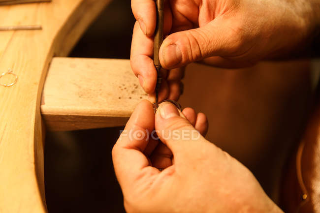 Close-up view of man working with tool and ring in workshop, cropped shot — Stock Photo