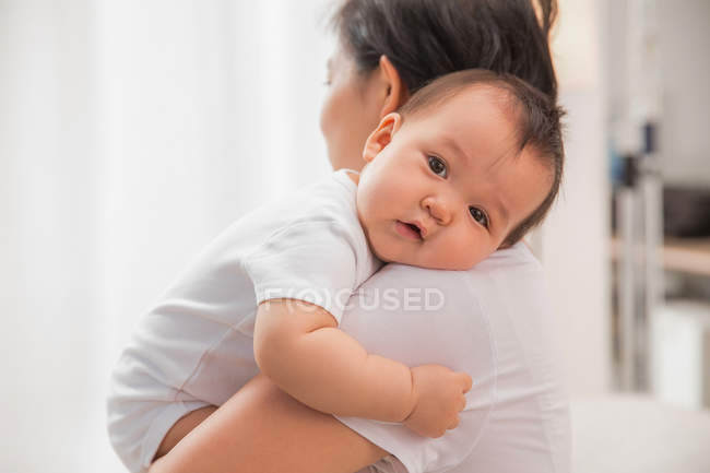 Seitenansicht einer Mutter mit entzückendem Baby, die in die Kamera schaut — Stockfoto