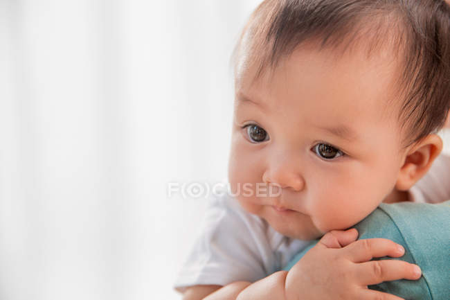 Обрезанный снимок матери, несущей очаровательного азиатского ребенка дома — стоковое фото