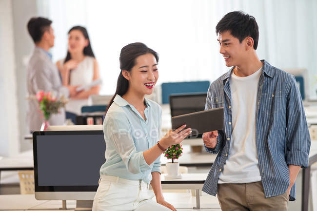 Sorrir jovem asiático empresário e empresária usando tablet digital juntos no escritório moderno — Fotografia de Stock