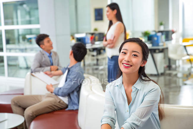 Belle heureux jeune asiatique femme d'affaires souriant à la caméra dans moderne bureau — Photo de stock