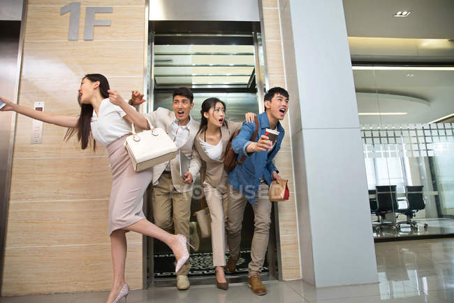 Young professional asian business people running from elevator to workplace in office — Stock Photo