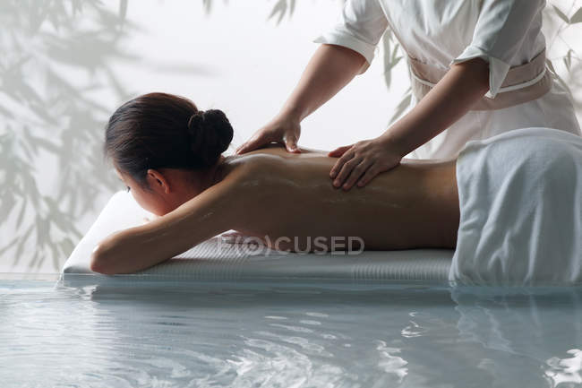 Side view of beautiful young woman receiving massage in spa, cropped shot — Stock Photo