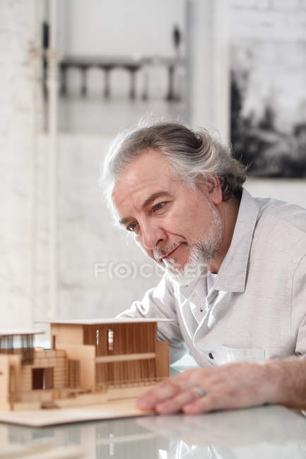 Професійний концентрований зрілий архітектор, що працює з будівельною моделлю на робочому місці — стокове фото