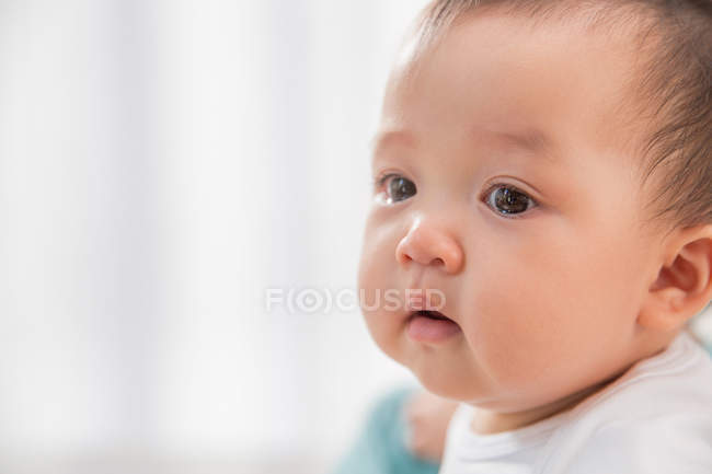 Primer plano retrato de hermosa asiático bebé mirando lejos en casa - foto de stock
