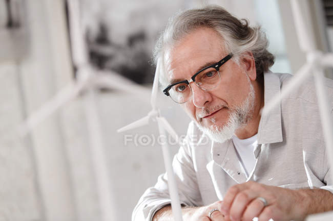 Concentrated mature architect in eyeglasses working with wind turbines in office — Stock Photo