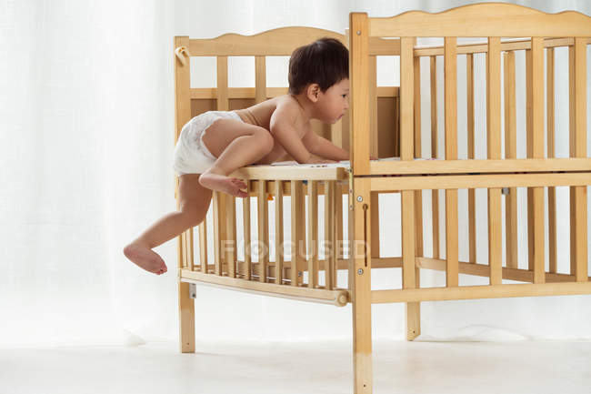 Вигляд на повну довжину чарівного азіатського малюка в підгузниках на ліжечку — стокове фото