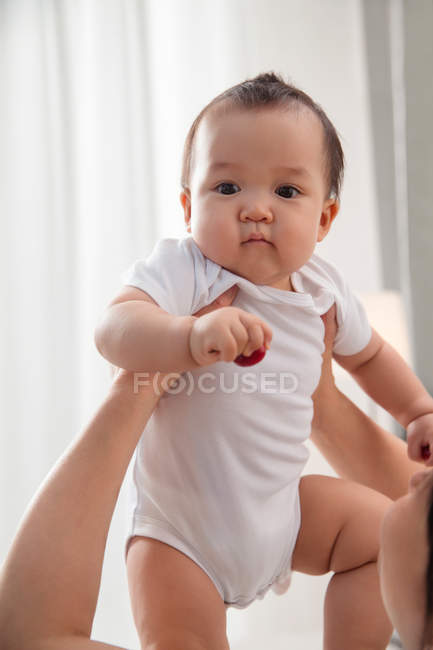 Cropped shot of young mother carrying adorable asian baby at home — Stock Photo
