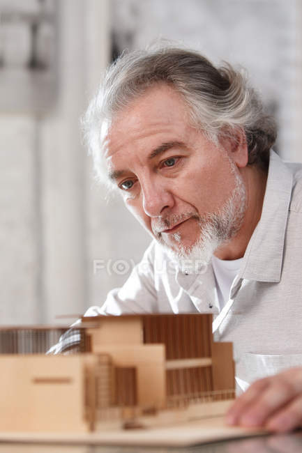 Professionista concentrato architetto maturo che lavora con il modello di costruzione sul posto di lavoro — Foto stock