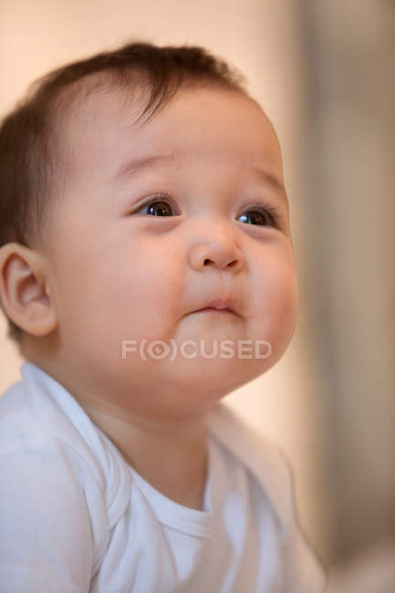 Портрет очаровательного азиатского младенца, смотрящего вдаль на дом — стоковое фото