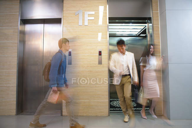 Verschwommene junge Geschäftsleute laufen im Büro in der Nähe von Aufzug — Stockfoto
