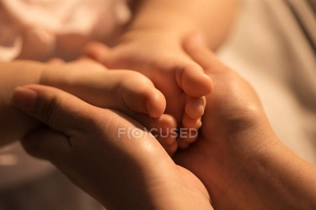 Cropped shot of mother holding feet of infant baby, close-up view — Stock Photo