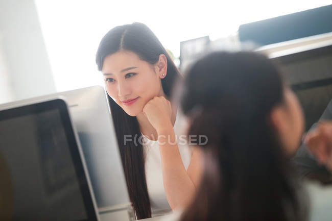 Sonriente joven asiático mujer de negocios trabajando con computadora en oficina - foto de stock
