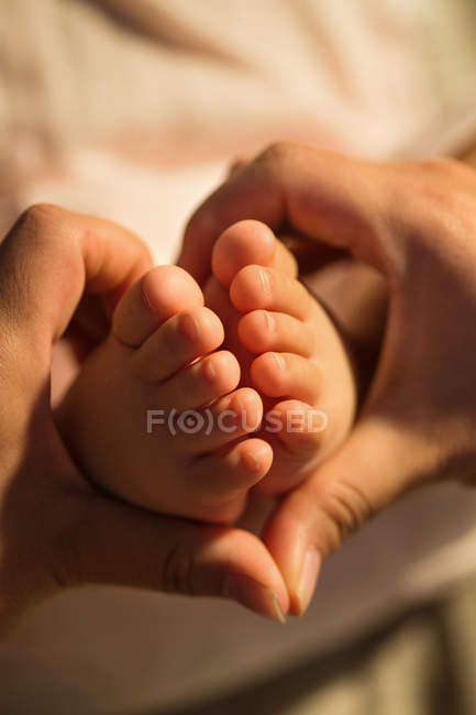 Обрізаний знімок матері тримає ноги немовляти, вид крупним планом — стокове фото