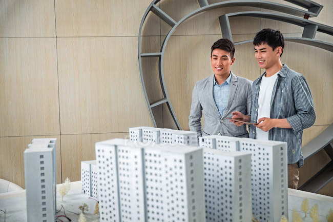Усміхнені молоді архітектори чоловічої статі дивляться на новий проект в офісі — стокове фото