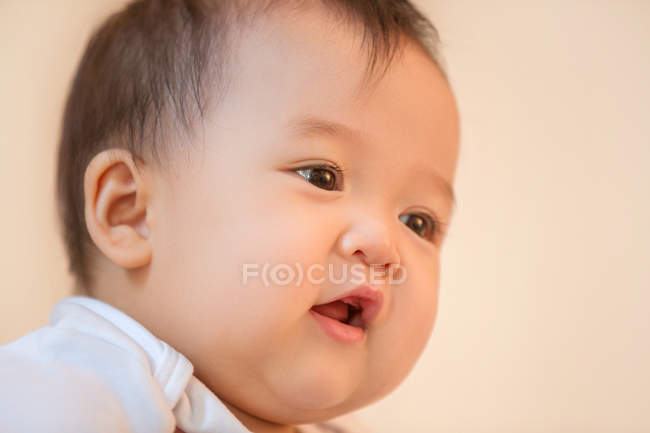 Close-up view of adorable asian infant baby looking away on pink background — Stock Photo