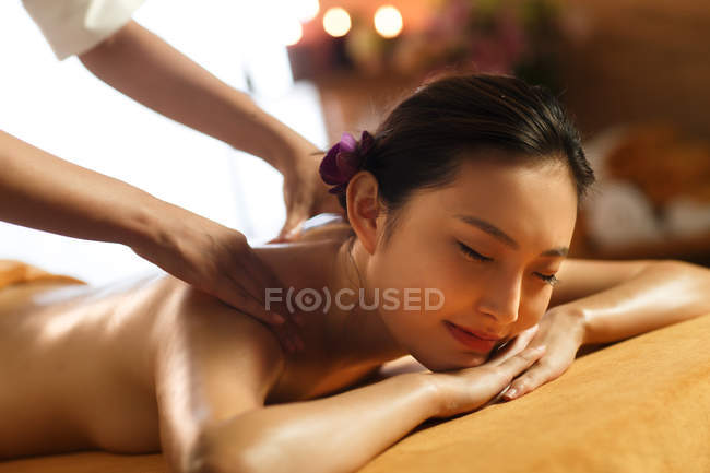 Обрізаний знімок привабливої молодої азіатки з закритими очима, що отримують масаж у спа-центрі — стокове фото
