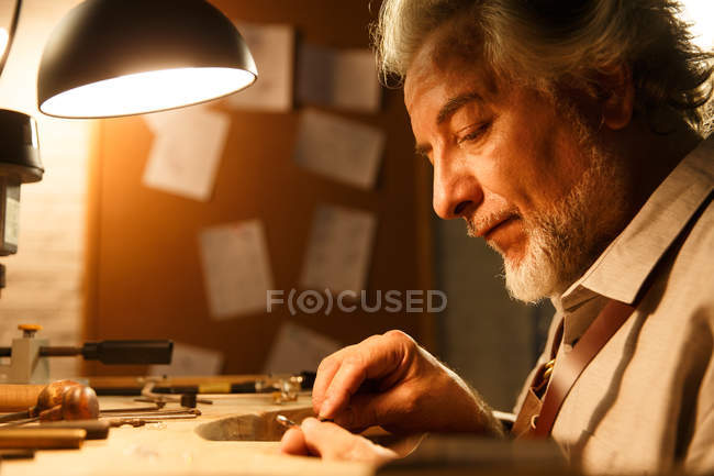 Close-up view of focused mature jewelry designer working with tools in workshop — Stock Photo