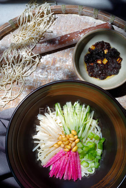 Вид сверху на вкусную азиатскую лапшу с нарезанными овощами и бобами — стоковое фото