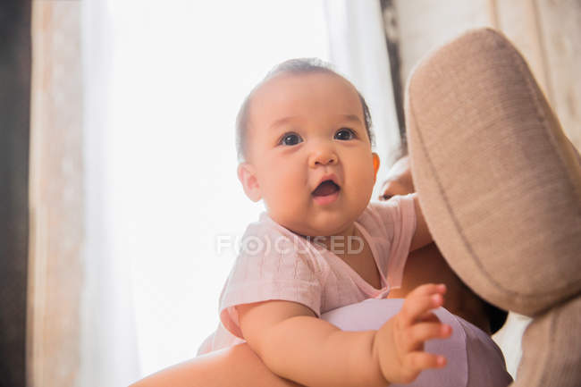 Side view of parent carrying adorable asian infant baby at home — Stock Photo
