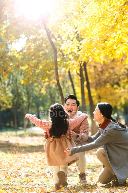 Feliz asiático hija corriendo a padres en otoñal parque - foto de stock