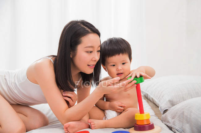Щаслива молода мати і дитина грають з барвистою іграшкою вдома — стокове фото