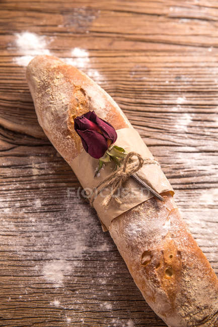 Top view of dry rose flower and bread on wooden table — Stock Photo