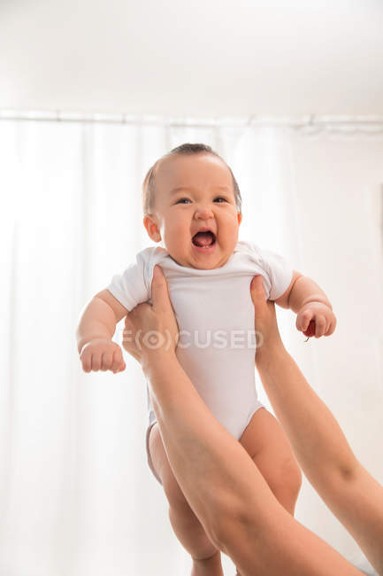 Cropped shot of mother holding unhappy infant baby crying at home — Stock Photo