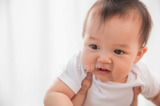 Recortado disparo de padre llevar adorable asiático bebé en casa - foto de stock