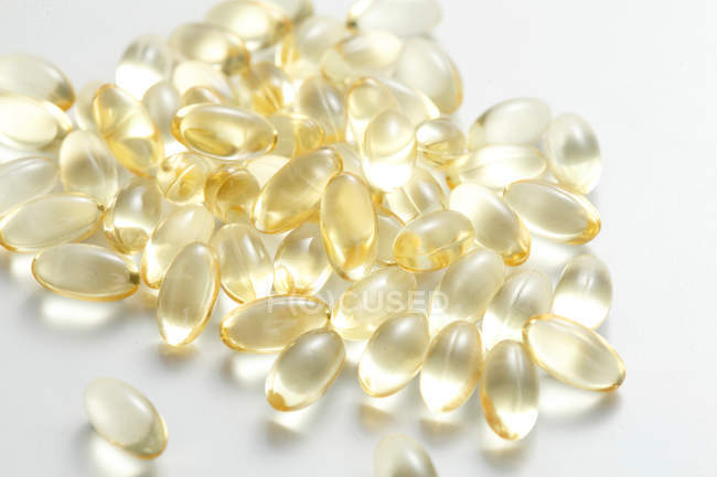 Розкидані жовтий таблетки на білій поверхні — стокове фото