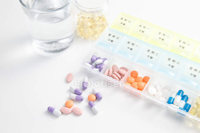 High angle view of pills in daily container on white surface — Stock Photo