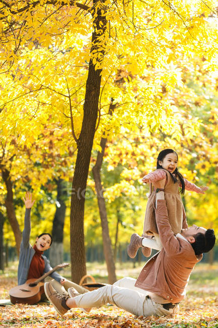 Heureux asiatique père levage fille dans automnal parc — Photo de stock