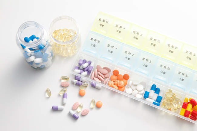 Hochwinkelaufnahme von Pillen im Tagesgebinde auf weißer Oberfläche — Stockfoto
