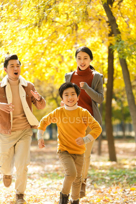 Pais felizes e filho correndo no parque outonal — Fotografia de Stock