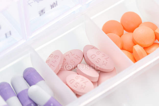 Primo piano delle pillole nel contenitore quotidiano sulla superficie bianca — Foto stock